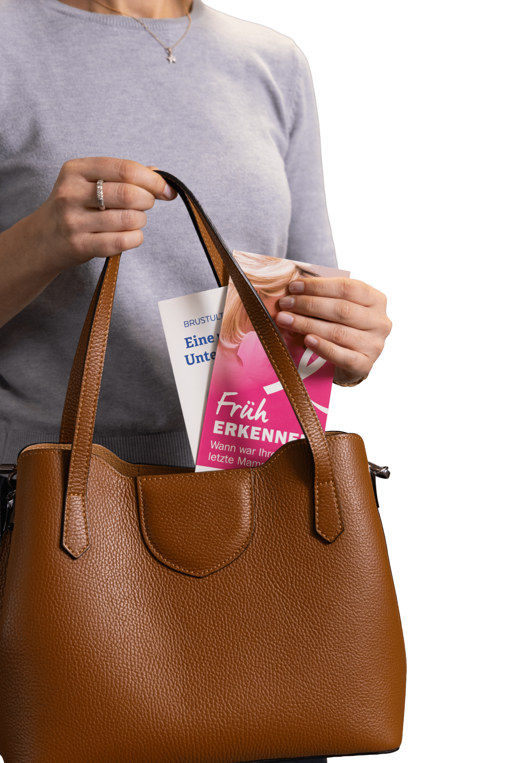 Tasche Mit Folder1 Frau legt Broschüre "Früh erkennen" in braune Handtasche